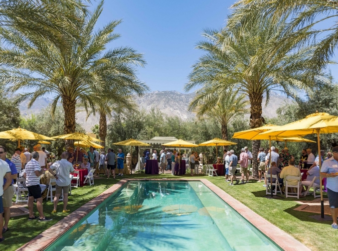 gathering outside near a pool with palm trees and mountain range in background