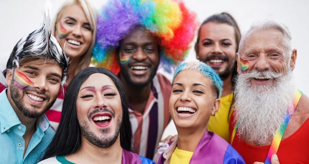 A diverse group of seven individuals from the LGBTQ community smiling at the camera
