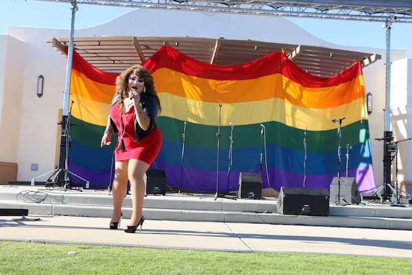 Fabeyonce performing at a past East Coachella Valley Pride festival in front of a large rainbow flag at Veteran's Park in Coachella